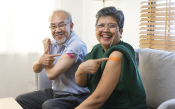 Asian couple get vaccinated with bandage on arm show thumb up sign in living room.